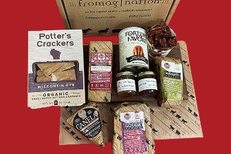A curated cheese and gourmet gift box featuring artisan crackers, assorted Roth cheeses, flavored spreads, nuts, and specialty accompaniments, arranged in front of a branded Fromagination packaging box.