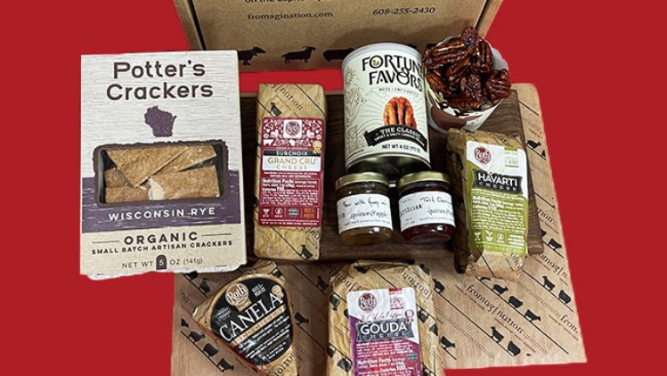A curated cheese and gourmet gift box featuring artisan crackers, assorted Roth cheeses, flavored spreads, nuts, and specialty accompaniments, arranged in front of a branded Fromagination packaging box.